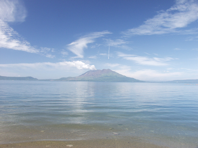 風のいたずらで乱れた雲と桜島からの長い噴煙が印象的な一枚です。